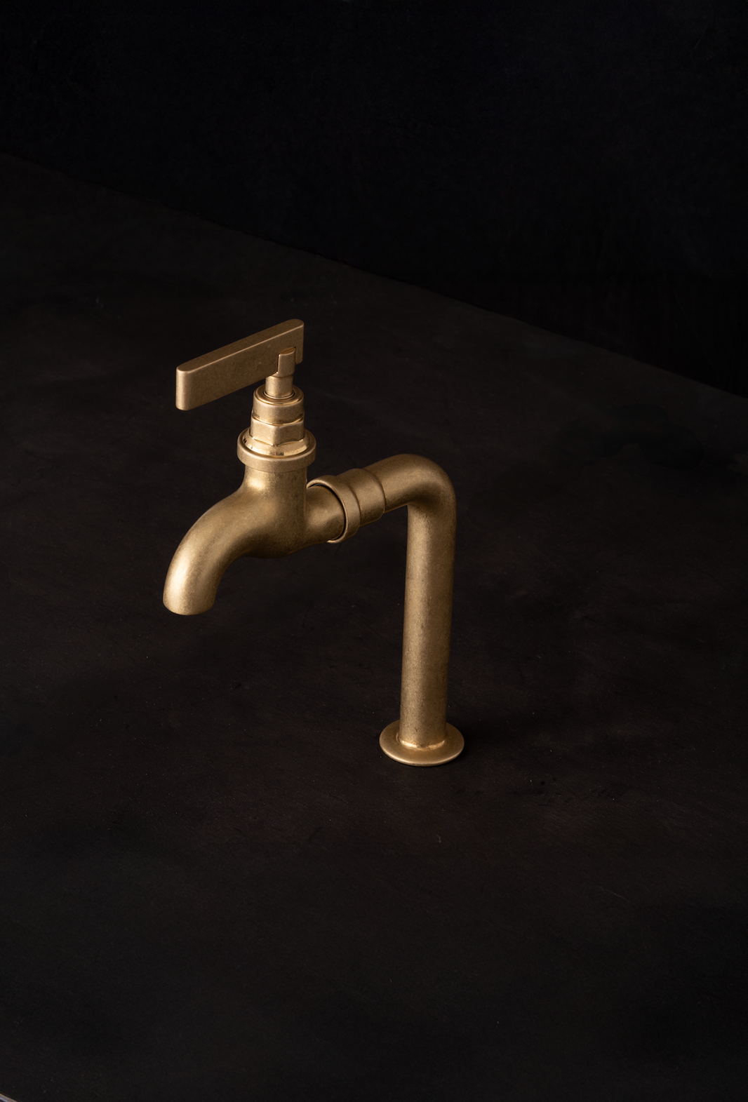 Studio Ore's Deck Mounted Bib Tap with a lever handle in unlacquered tumbled brass.