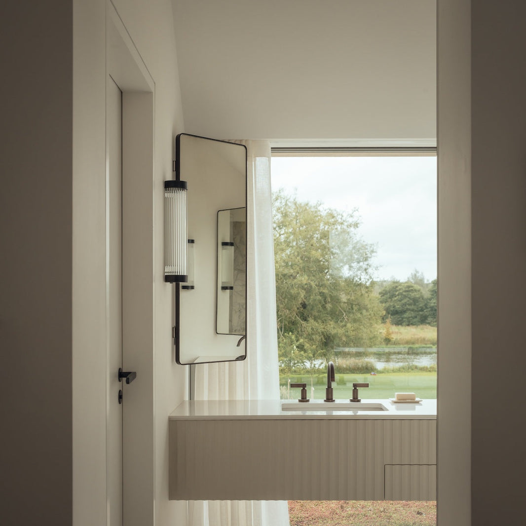 Studio Ore's deck mounted three hole basin taps are installed on a cream coloured basin. Behind is a large floor to ceiling window looking out to the river.