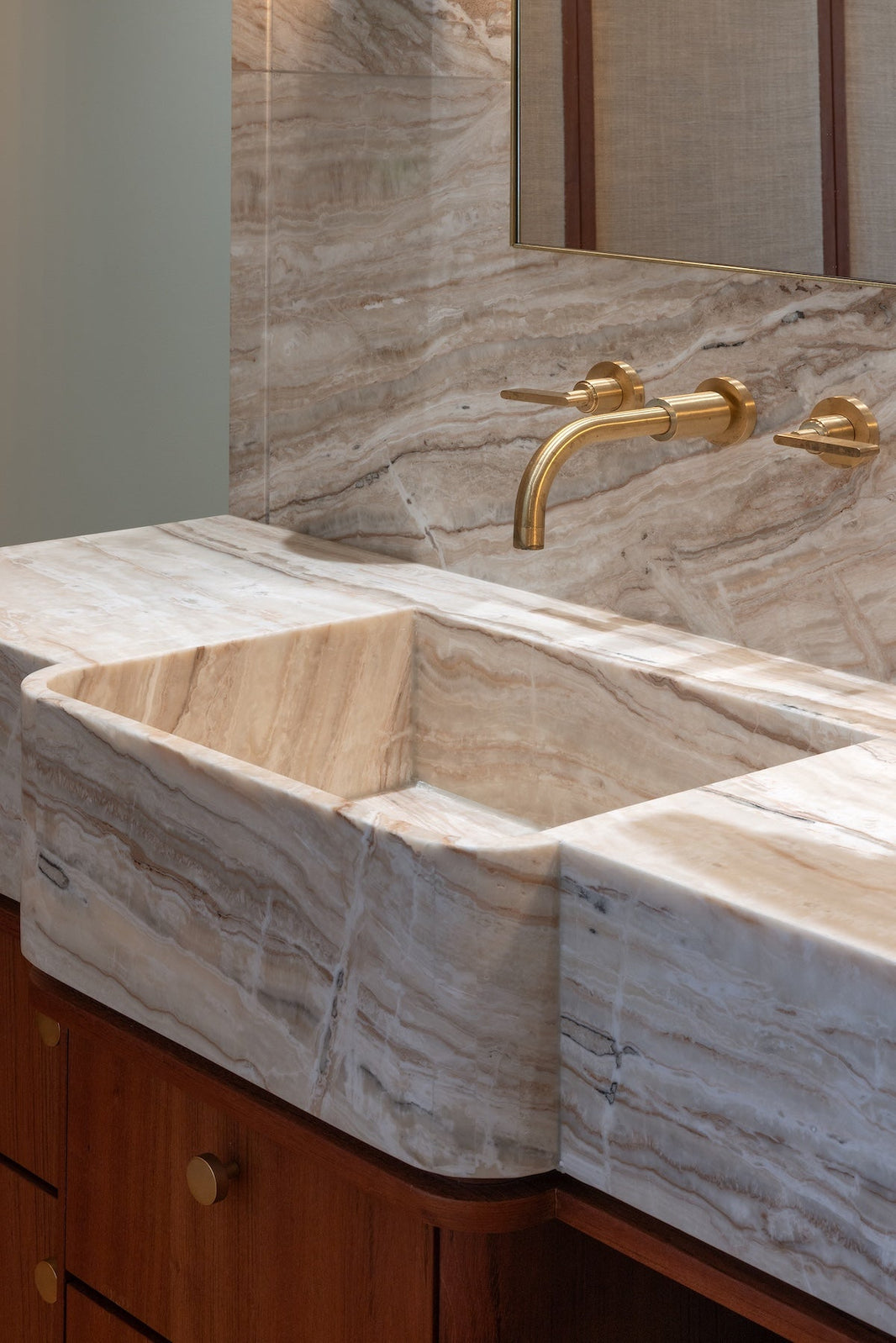 Studio Ore's wall mounted basin tap in brushed brass sits in a modern bathroom.