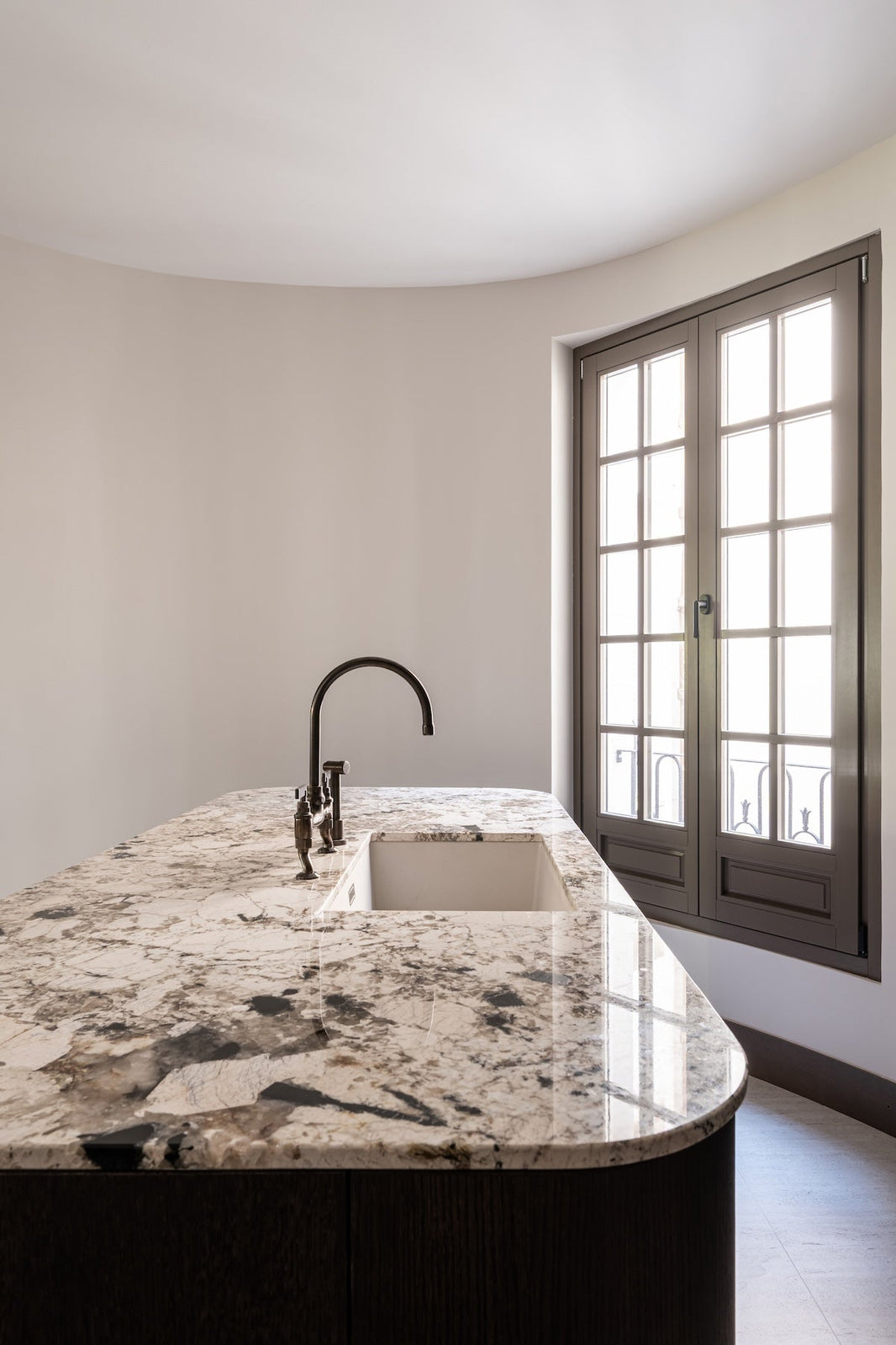 Studio Ore's kitchen bridge mixer in lacquered bronze stands over a farmhouse basin. 