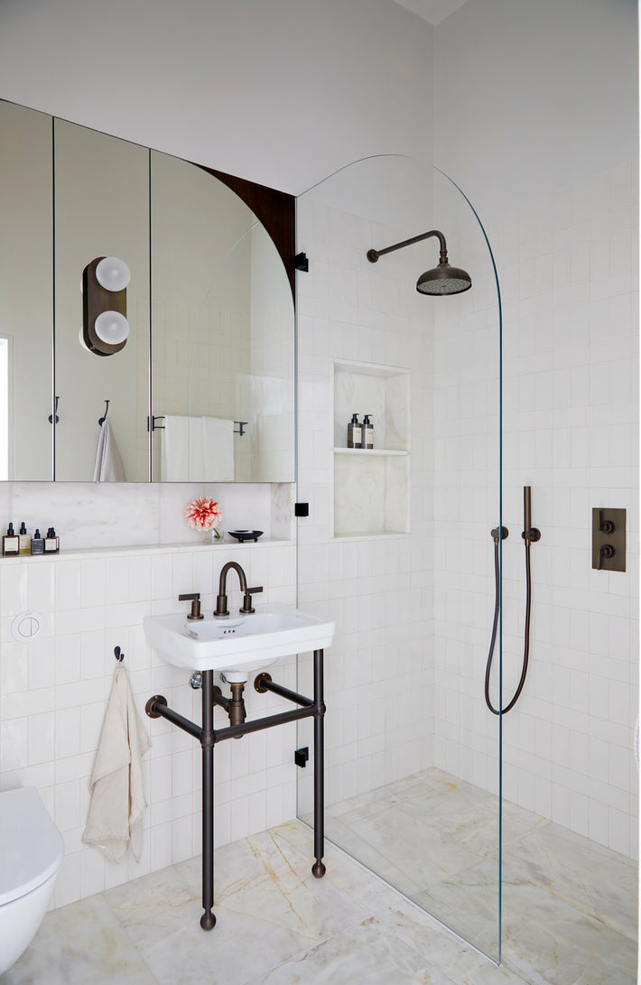 Studio Ore's brass fittings complete this bathroom. It features lacquered bronze basin taps, an overhead shower, wall-mounted hand shower and in-wall thermostat.