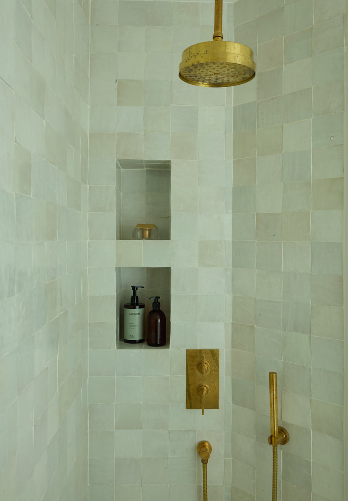 Tiled shower with brass shower accessories from Studio Ore