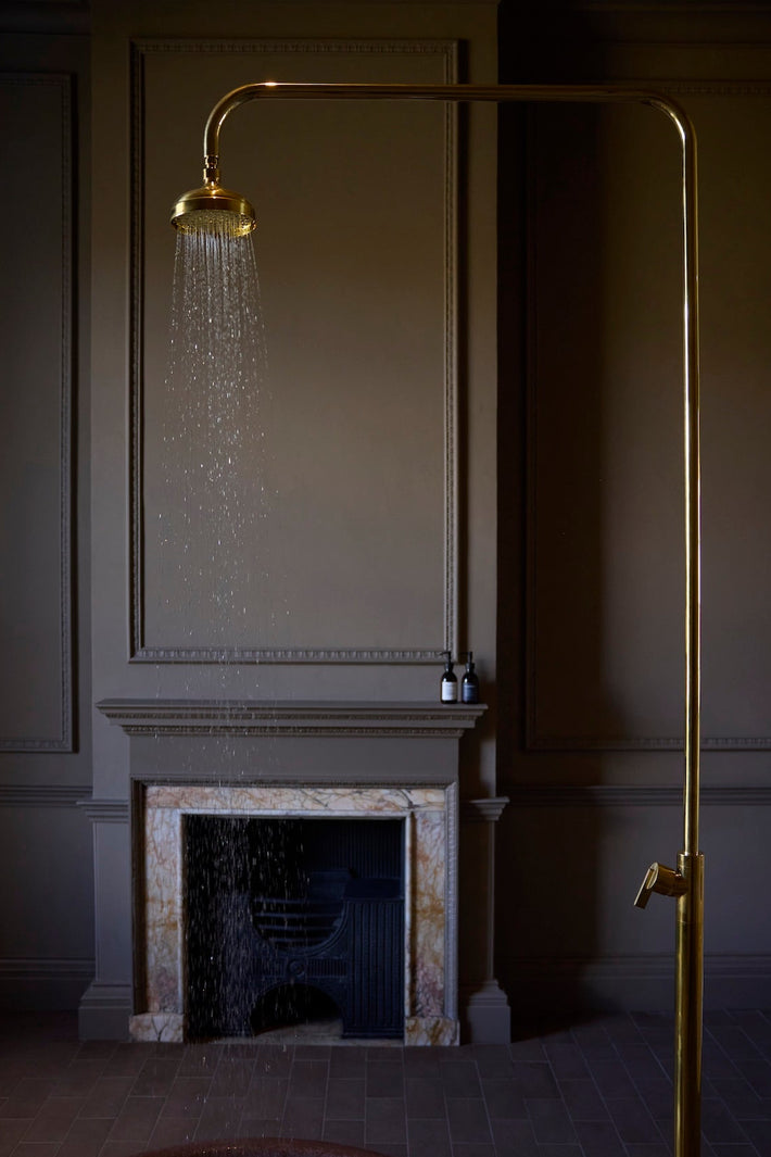 Studio Ore's bespoke free-standing shower with a traditional shower rose in polished brass is found at Denton Hall. 