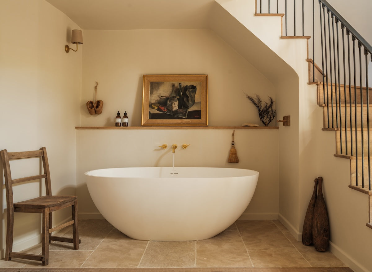 Studio Ore's old brass bath tap is wall mounted over a minimal freestanding bath. 