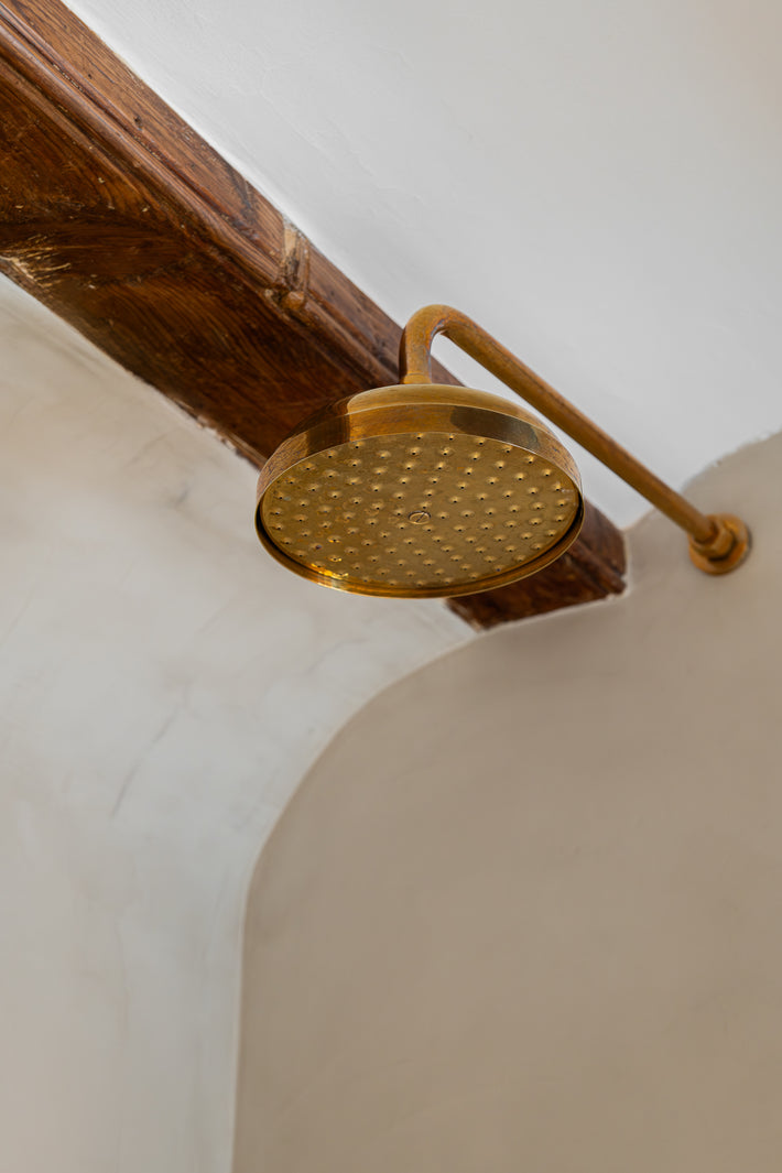 Studio Ore's solid brass shower fittings and accessories are found in the bathroom of this Barcelona apartment. Here, the Victorian shower rose and arm is wall-mounted. Also in unlacquered polished brass, a characterful patina has developed. 