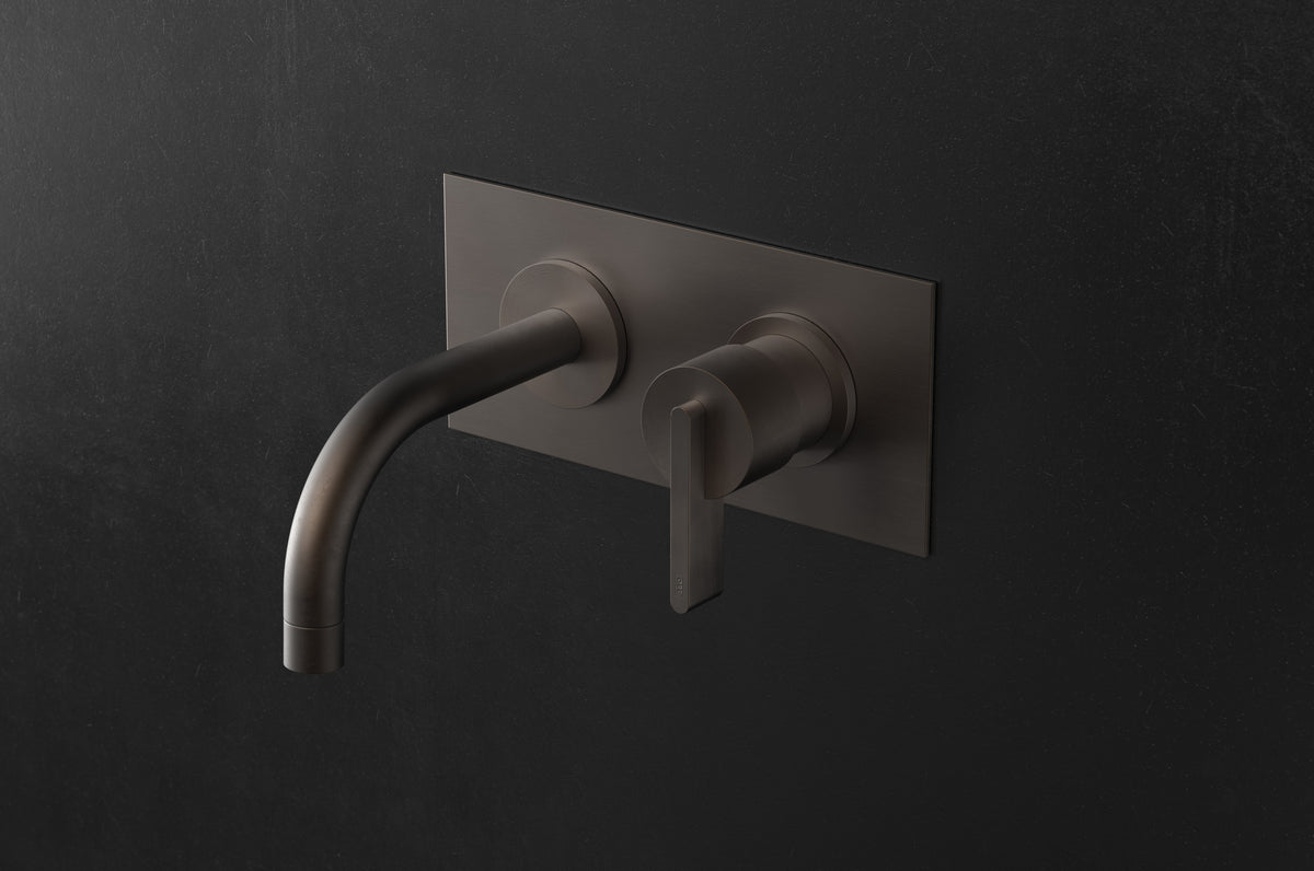 Studio Ore Chapter Three Two Hole Wall Mounted Basin Mixer with Curved Spout and Backplate with Lever handle in bronze