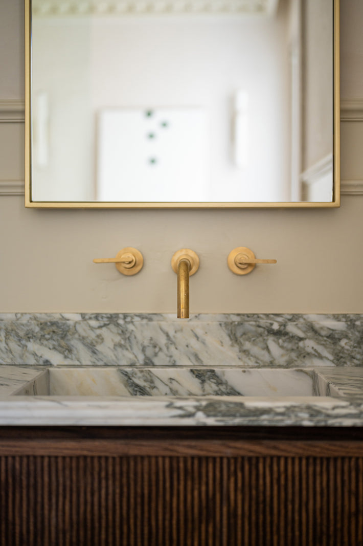 Studio Ore fittings are found in the bathroom of this home designed by Tristan Domecq. The taps are mounted on the wall, above a marble basin. 