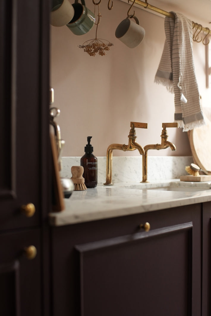 Studio Ore's pair of deck mounted bib taps in unlacquered polished brass. 